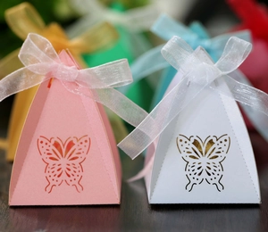 Close-up of laser-cut hollow butterfly candy boxes in pink and white with organza ribbons