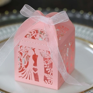 Detailed pink laser-cut wedding favor box with bride and groom silhouette in a gold-rimmed plate