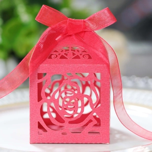Close-up of laser-cut rose hollow candy box with elegant magenta ribbon on a porcelain plate