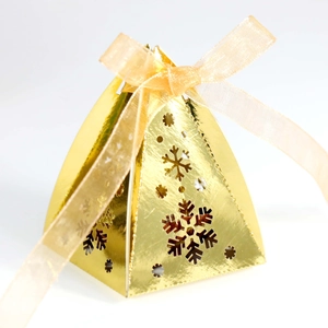 Macro-opname van gouden piramide geschenkdoos met uitgesneden sneeuwvlok en lint