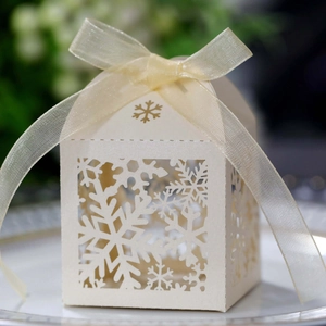 Macro detail of white laser-cut snowflake wedding candy box with cream ribbon bow