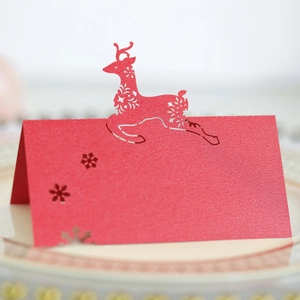 Close-up of red laser-cut place card with reindeer and snowflake pearl paper texture