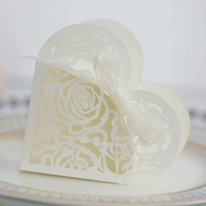 Detail of laser-cut heart candy box with ivory rose pattern and satin ribbon bow