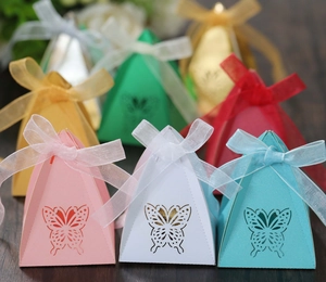 Macro view of pyramid wedding candy boxes with hollow butterfly design and ribbon bow