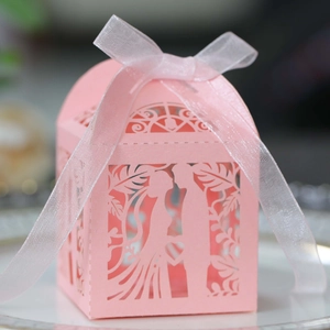 Detail of pink laser-cut wedding favor box with heart patterns and ribbon bow