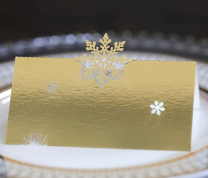 Macro detail of laser-cut gold snowflake place card with pearlescent finish on a plate