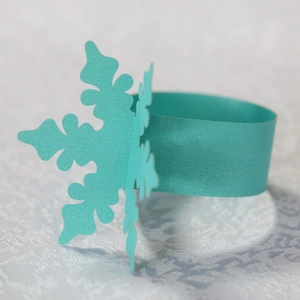 Dettaglio macro del portatovagliolo in carta verde menta con fiocco di neve tagliato al laser