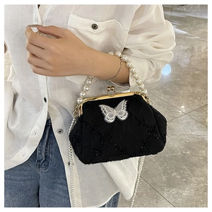 Detail of black quilted handbag with white butterfly accent and pearl handle