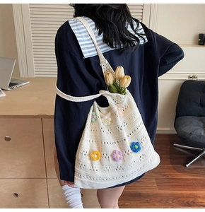 Detail of white crochet shoulder bag featuring 3D colorful knit flowers and wave patterns