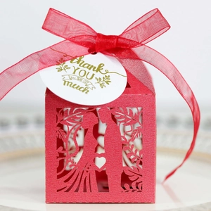 Close-up of red laser-cut wedding favor box with ribbon and gold-stamped Thank You tag
