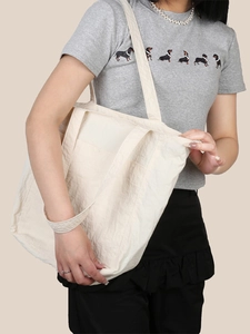 Dettaglio della borsa tote crema che mostra il design a doppio manico e il tessuto nylon