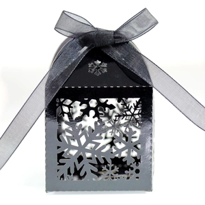 Détail d'une boîte à bonbons noire évidée flocon de neige avec nœud en ruban satin