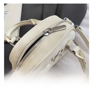 Close-up of the silver zipper and bow detail on the cream mini bowling bag