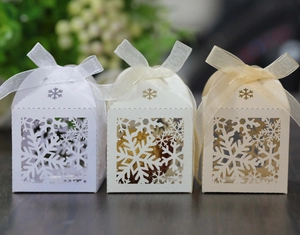 Detailed laser-cut snowflake gift boxes in white and champagne with ribbon bows