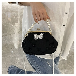 Detail of black quilted handbag featuring white lace butterfly and pearl bead handles