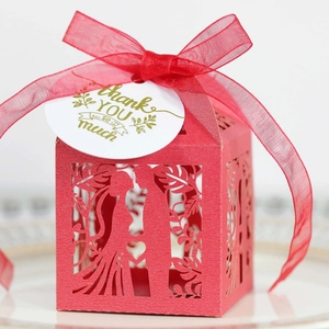 Detail of red laser-cut candy box with bride and groom silhouette and thank you tag
