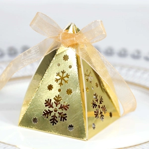 Detail van gouden driehoekige geschenkdoos met sneeuwvlok uitsnijdingen en lintstrik