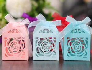 Detail of laser-cut rose hollow candy boxes with elegant silk ribbons in various colors