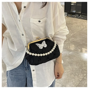Detail of vintage black kiss-lock bag with white butterfly appliqué and pearl straps