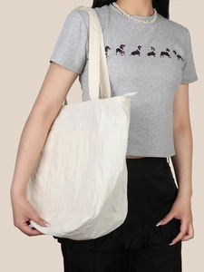 Dettaglio della borsa tote bianco sporco con texture pieghettata e tracolla ampia