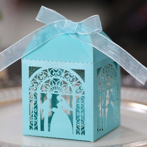 Detail of sky blue laser-cut wedding candy box with bride and groom silhouette and ribbon