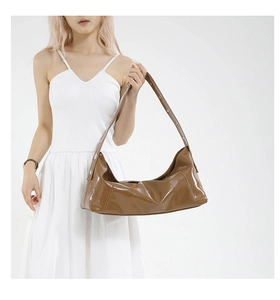 Detail of glossy brown underarm bag featuring silver eyelet studs on the shoulder strap