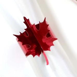 Macro shot of bright red maple leaf napkin ring with metallic luster on white cloth