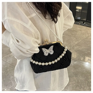 Detail of black tweed frame bag with lace butterfly, pearl straps and vintage clasp