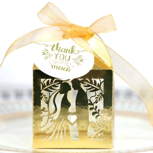Detail of laser-cut gold wedding favor box with bride and groom silhouette and ribbon