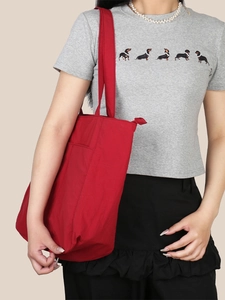 Vista laterale di una grande borsa tote in tela rossa indossata per il look quotidiano