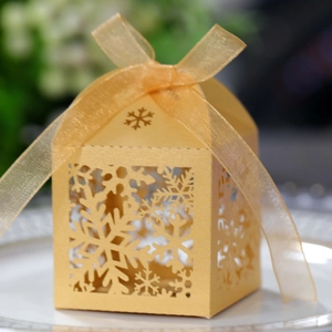 Detailed view of laser-cut gold snowflake gift box with ribbon for wedding favors