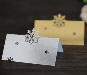 Detail of laser-cut snowflake place cards in gold and silver finish on wood table