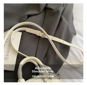 Close-up of white adjustable faux leather strap with silver metal buckle on handbag