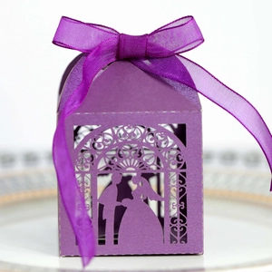 Detail of purple laser-cut wedding favor box with bride groom silhouettes and ribbon