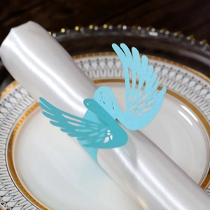 Macro view of a laser-cut light blue bird-shaped paper napkin ring on a white napkin