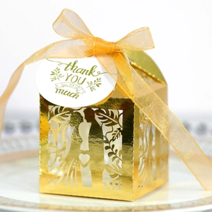 Close-up of laser-cut gold wedding favor box with heart silhouette and thank you tag
