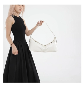 Close-up of a white glossy leather hobo bag with a stylish metal eyelet strap on model