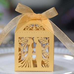 Detailed view of laser-cut heart and couple silhouette on a golden wedding candy box