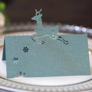Macro view of dark green pearlescent name card with laser-cut reindeer and snowflakes