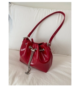 Détail du sac seau en cuir verni rouge brillant avec cordon en chaîne argentée et perles en métal