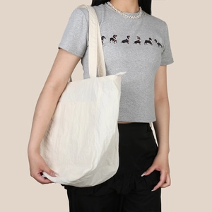 Dettaglio della borsa tote beige grande con superficie in nylon strutturato e tracolla