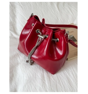 Détail du sac seau en cuir verni rouge avec cordon de serrage et chaîne argentée