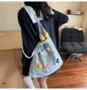 Dettaglio della borsa in maglia azzurra fatta a mano con applicazioni di fiori 3D colorati