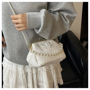 Detail of white fabric bag with butterfly embroidery, pearl straps and metal clasp