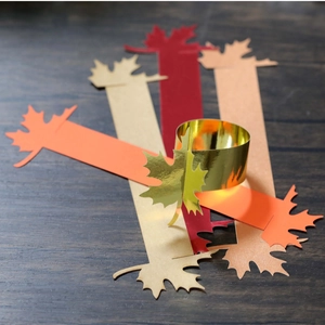 Close-up of maple leaf napkin rings in gold and red for Thanksgiving table decor