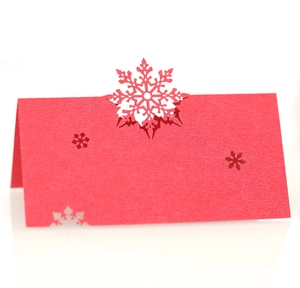 Macro shot of red laser-cut paper place card featuring delicate hollow snowflake design