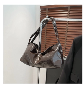 Detail of dark brown wax leather crescent bag featuring metallic eyelets on wide strap