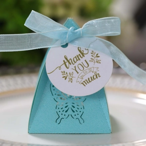 Macro view of light blue gift box with laser-cut butterfly and 'thank you' tag