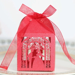 Close-up of laser-cut red wedding favor box with glitter texture and ribbon bow
