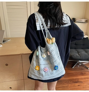Detail of light blue crochet tote bag featuring colorful knitted flowers and floral accents